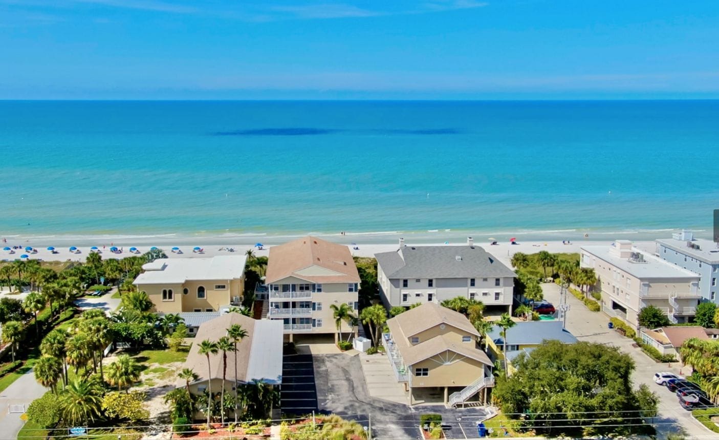Una zona residencial costera con propiedades frente al mar, cielo despejado y mar tranquilo.