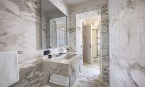 Une salle de bain avec un lavabo en marbre, un grand miroir et un porte-serviettes.