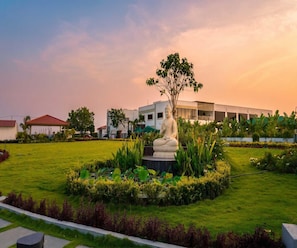 A statue in a landscaped garden with a modern building in the background.