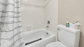 A bathroom with a bathtub, toilet, and shower curtain. - Spacious Comfort Haven (Montgomery)