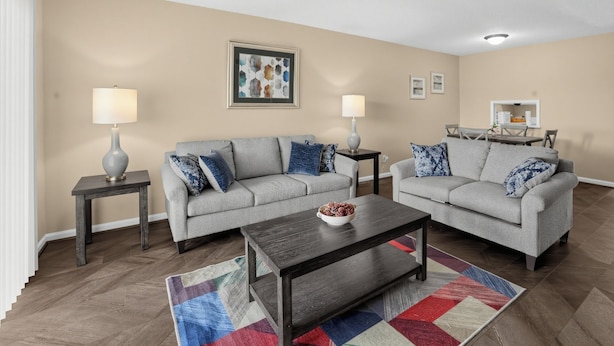 A living room with two grey sofas, a dark wooden coffee table, and a colorful rug. - Spacious Comfort Haven (Montgomery)