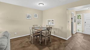 A dining area with a table and chairs, a kitchen area with appliances, and a door leading outside. - Spacious Comfort Haven (Montgomery)