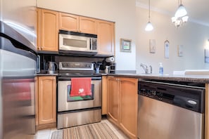 A modern kitchen with stainless steel appliances, wooden cabinets, and a built-in dishwasher. - StayToronto - Downtown Yonge Core Suites (Toronto)