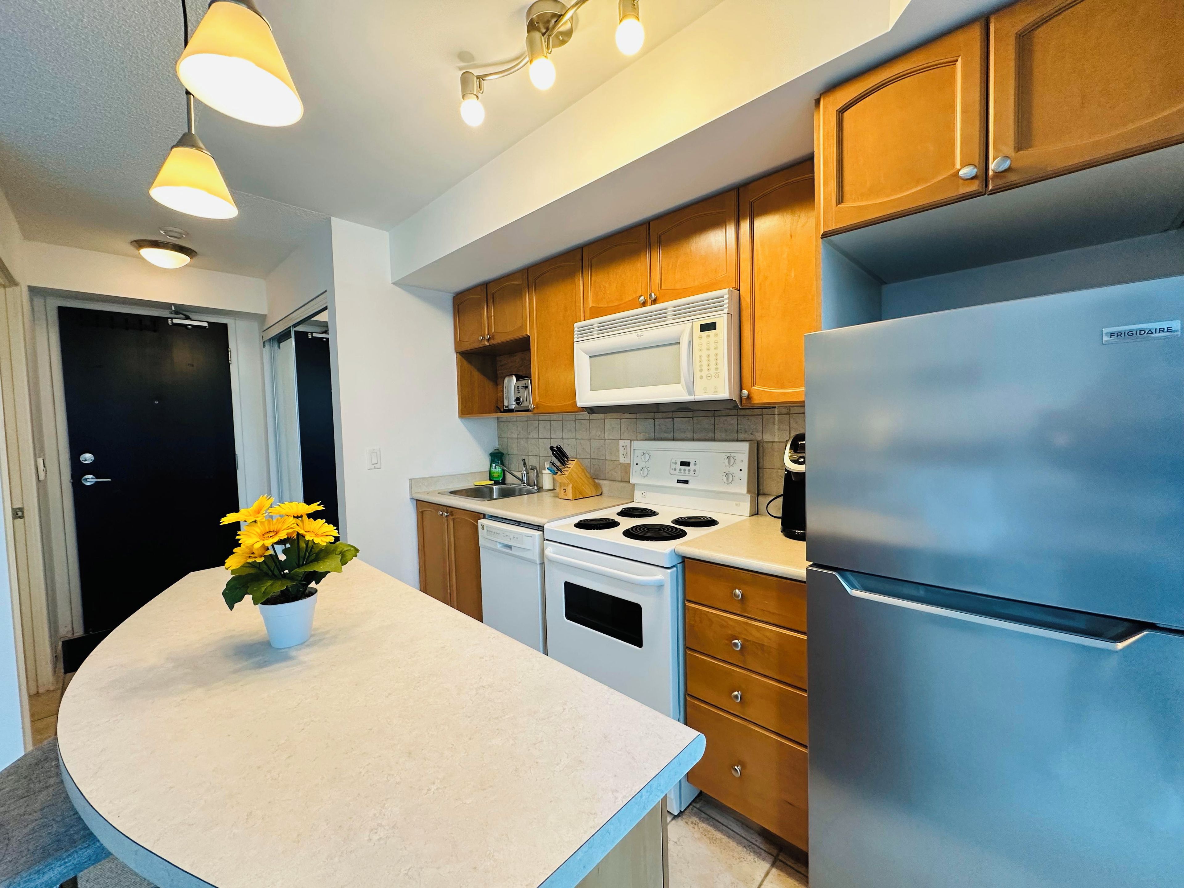 Una cocina moderna con armarios de madera, un refrigerador de acero inoxidable, un microondas y una estufa.