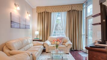 Una sala de estar con sofá, sillón, mesa de centro y televisor sobre un mueble de madera.