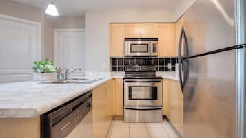 Una cocina moderna con electrodomésticos de acero inoxidable, armarios de madera y una encimera de mármol.