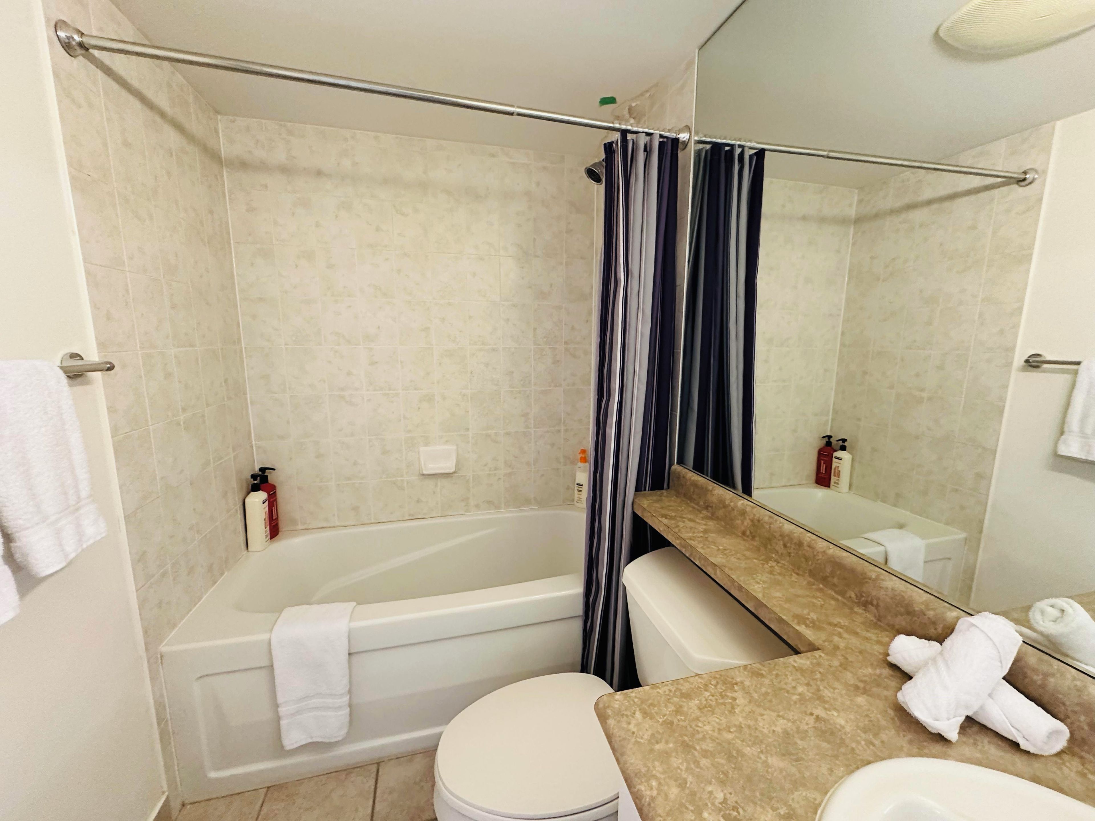 A bathroom with a bathtub, toilet, and a sink with a mirror.