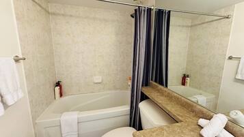 A bathroom with a bathtub, toilet, and a sink with a mirror.