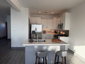 A modern kitchen with a central island, stainless steel appliances, and a minimalist design. - NEW Coastal property with AMAZING waterfront views!! (Bacliff)