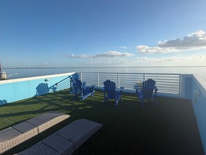 A deck with lounge chairs and a table, overlooking a body of water. - NEW Coastal property with AMAZING waterfront views!! (Bacliff)