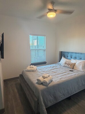 A bedroom with a bed, a ceiling fan, a window with blinds, and a wall-mounted TV. - NEW Coastal property with AMAZING waterfront views!! (Bacliff)