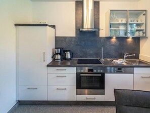 A compact kitchen with a built-in oven, a coffee maker, and a dishwasher. - Holiday Apartment With 1 Bedroom (Esens)