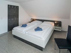 A modern hotel room with a large bed, two bedside tables with lamps, a chair, and a dark accent wall. - Holiday Apartment With 1 Bedroom (Esens)