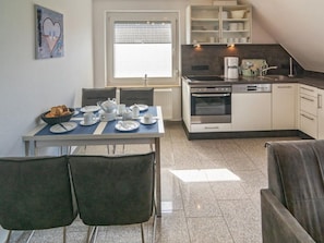 A compact kitchen with a dining table set for two, a coffee maker, and a refrigerator. - Holiday Apartment With 1 Bedroom (Esens)