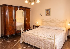 A bedroom with a bed, a wardrobe, a nightstand, a lamp, and a wall-mounted picture. - Antica Corte Di Pisa Near Train Station (Pisa)