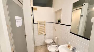 Une salle de bain comprenant des toilettes, un bidet, un lavabo et un porte-serviettes.
