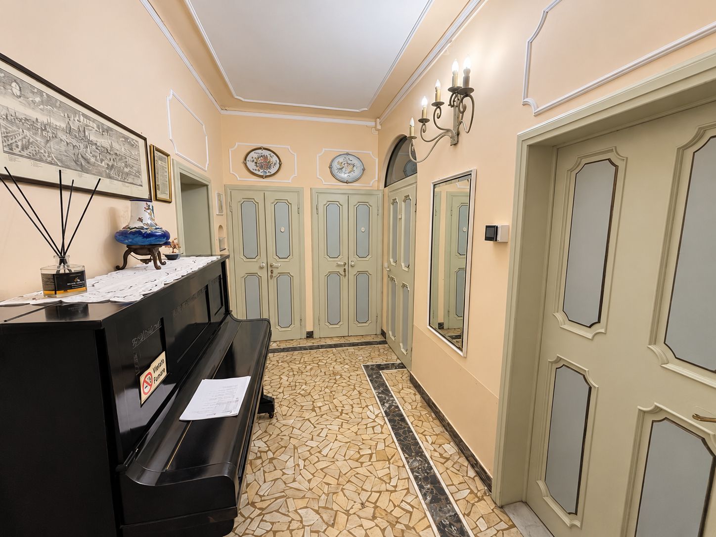 A hallway with a piano, a wall-mounted clock, and a door with a mirror.
