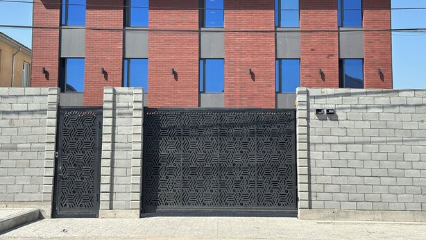 A modern building with a brick facade, multiple windows, and a decorative metal gate. - Dream Jaiylgan (Bishkek)