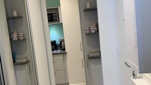 Una cocina moderna con armarios blancos, un microondas y una cafetera.
