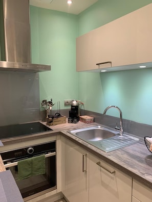 Una cocina moderna con una campana de acero inoxidable, un lavamanos doble y un horno empotrado.
