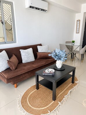 Ein modernes Wohnzimmer mit einem braunen Sofa, einem Glastisch und einer dekorativen Vase.