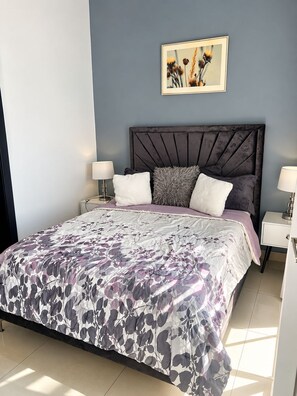 A bedroom with a large bed, two bedside tables, a headboard, and a framed picture on the wall. - Boca Chica Escape  Pool • 3 Min to Beach (Santo Domingo)