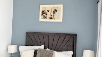 Een slaapkamer met een bed, twee nachtkastjes, een plafondventilator en een aan de muur hangend schilderij.