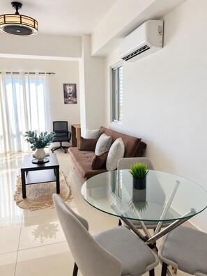 A modern living room with a glass table, a brown sofa, and a television. - Boca Chica Escape  Pool • 3 Min to Beach (Santo Domingo)