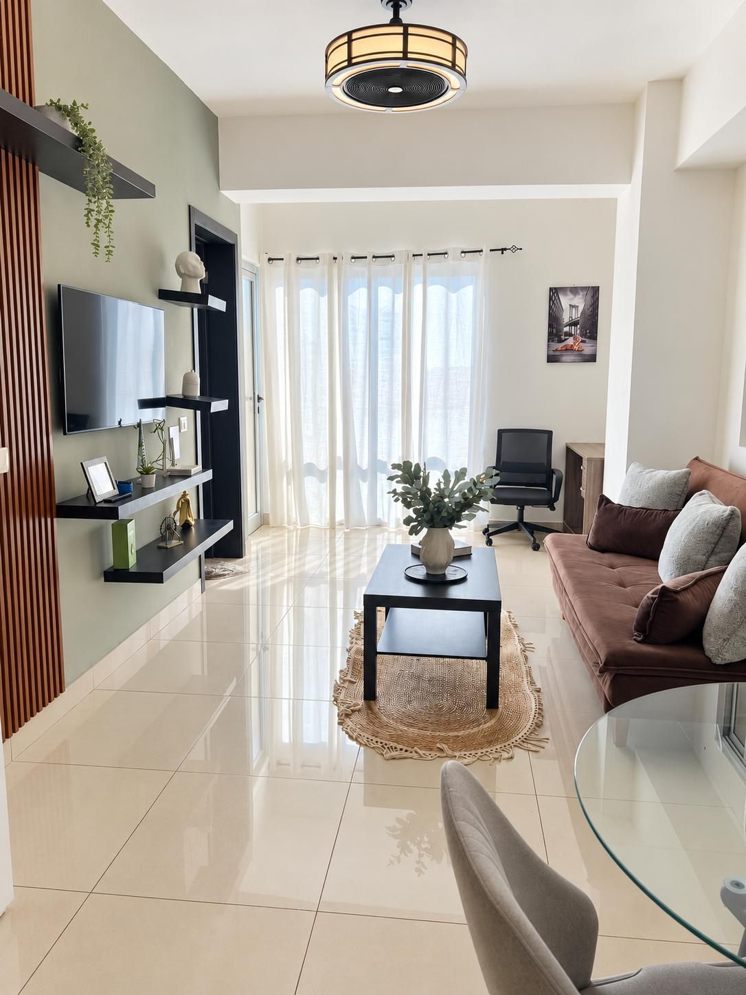 Een moderne woonkamer met een flatscreen televisie, een bank, een glazen salontafel en een eethoek met een glazen tafel.
