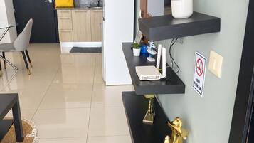 A modern kitchen with a refrigerator, a sink, and cabinets. There is a dining area with a table and chairs.