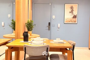 A dining area with a wooden table set for two, chairs, a potted plant, and a framed picture on the wall. - FR Bueno de Alto Padrão Lazer Premium (Goiânia)