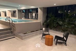 Ein Poolbereich mit Stufen zum Pool, zwei Stühlen und einem Holztisch.