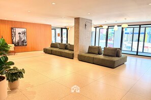 Eine großzügige Lobby mit modernem Design, inklusive einer geräumigen Sitzecke mit Sofas und einer Zimmerpflanze.