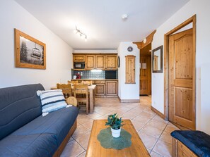 A compact living space with a sofa, dining table, and kitchen area. - Bright apartment near slopes - 6 guests (Les Menuires)
