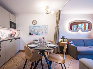 A compact living space with a dining area, kitchenette, and a cozy seating area. - Bright apartment near the slopes (Les Menuires)