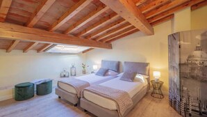 A bedroom with two beds, wooden beams, a skylight, bedside tables, and a wall-mounted lamp. - FLORENCE DUPLEX RETREAT WITH ICONIC DUOMO & BELL TOWER VIEWS (Firenze)