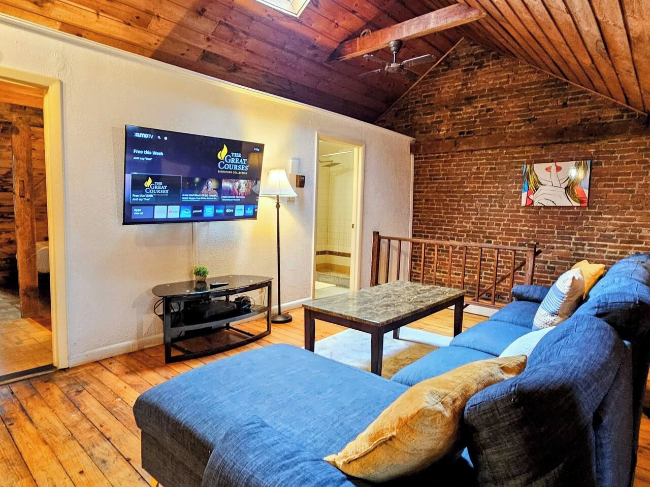 Ein gemütliches Wohnzimmer mit Fernseher, einer Couch, einem Tisch und einer Lampe.