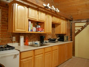 Una cocina con armarios de madera, un microondas, un hervidor y un lavamanos.