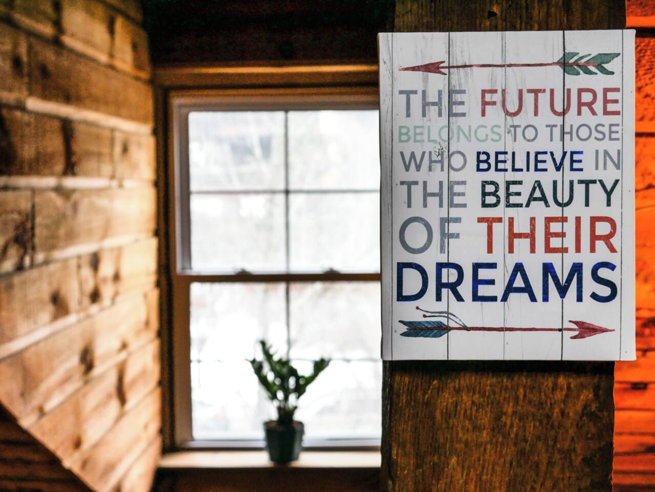 Une affiche avec un texte motivant, dans une pièce au style rustique, avec des murs en bois et une fenêtre.