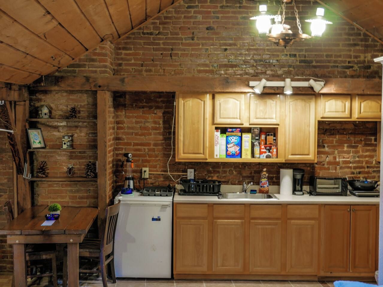 Eine Küche mit Holzschränken, einem Kühlschrank und einer Arbeitsplatte mit verschiedenen Geräten und Gegenständen.