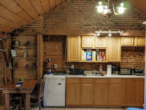 A kitchen with wooden cabinets, a refrigerator, and a countertop with various appliances and items.