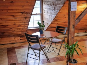 Un intérieur en bois avec une table et des chaises, une plante en pot et un panneau accroché au mur.