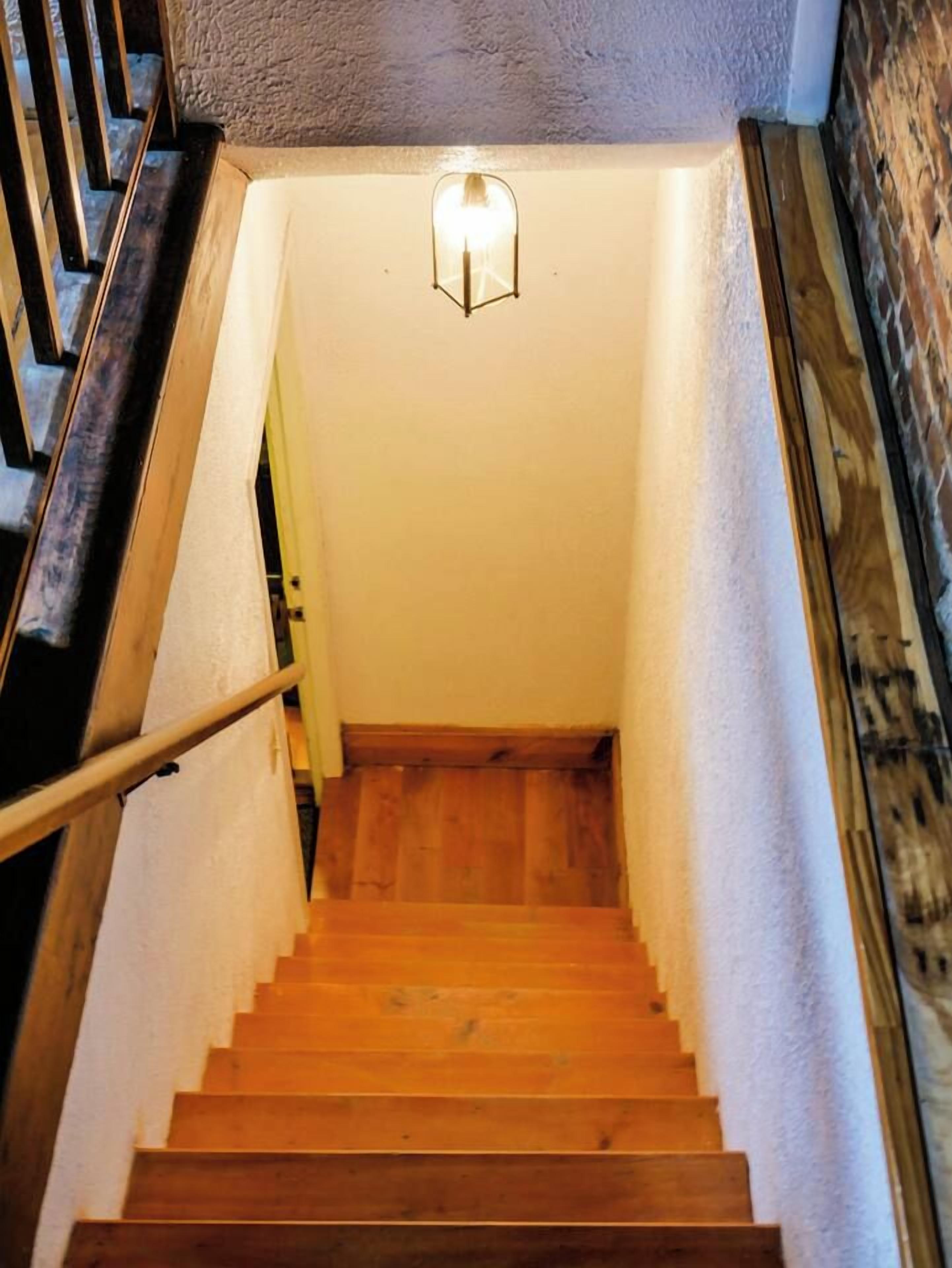 A wooden staircase with a handrail, leading to a landing with a light fixture.