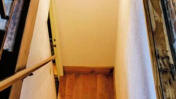 A wooden staircase with a handrail, leading to a landing with a light fixture.