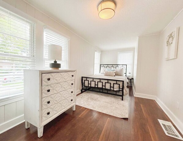 Un dormitorio con cama, cómoda y ventana con persianas.