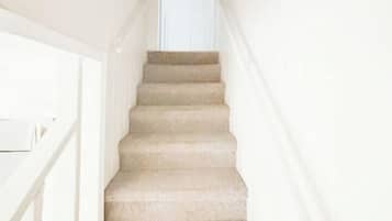 A staircase with a white railing leading to a door at the top.