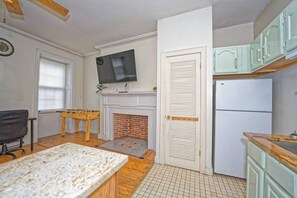 Una cucina con un camino, una televisione montata sopra e un frigorifero.