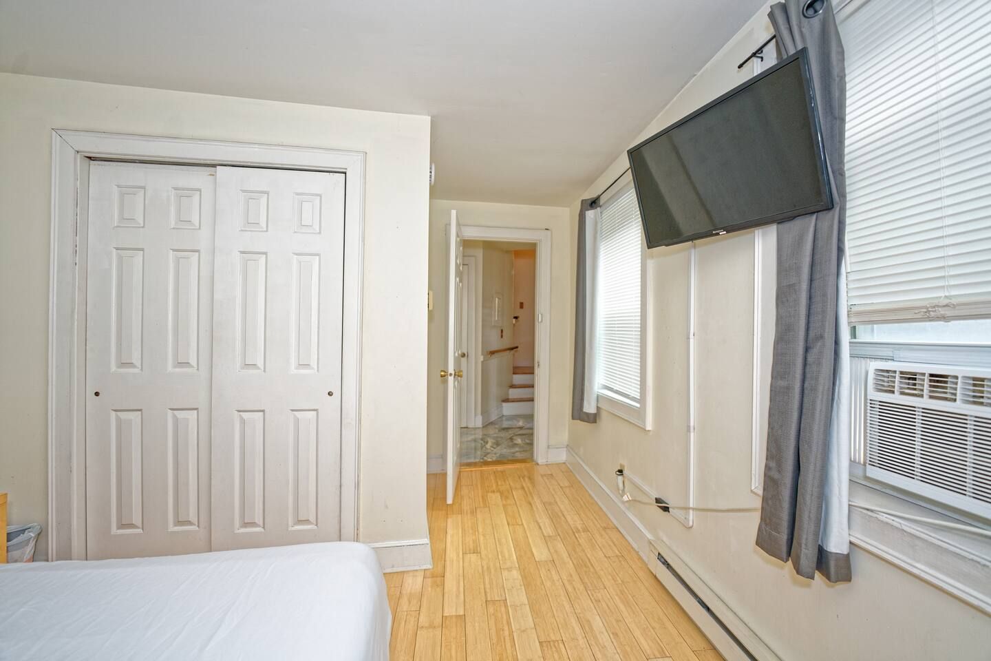 Un dormitorio con una cama, una puerta, una escalera y un televisor montado en la pared.