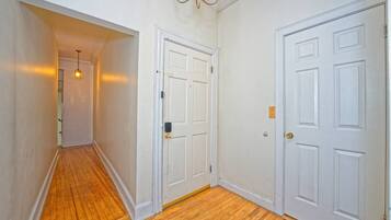 A hallway with wooden flooring, white walls, and two white doors with brass handles.