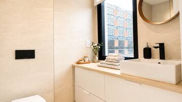 Ein modernes Badezimmer mit Toilette, Waschtisch und einem Fenster mit Blick auf ein Gebäude.